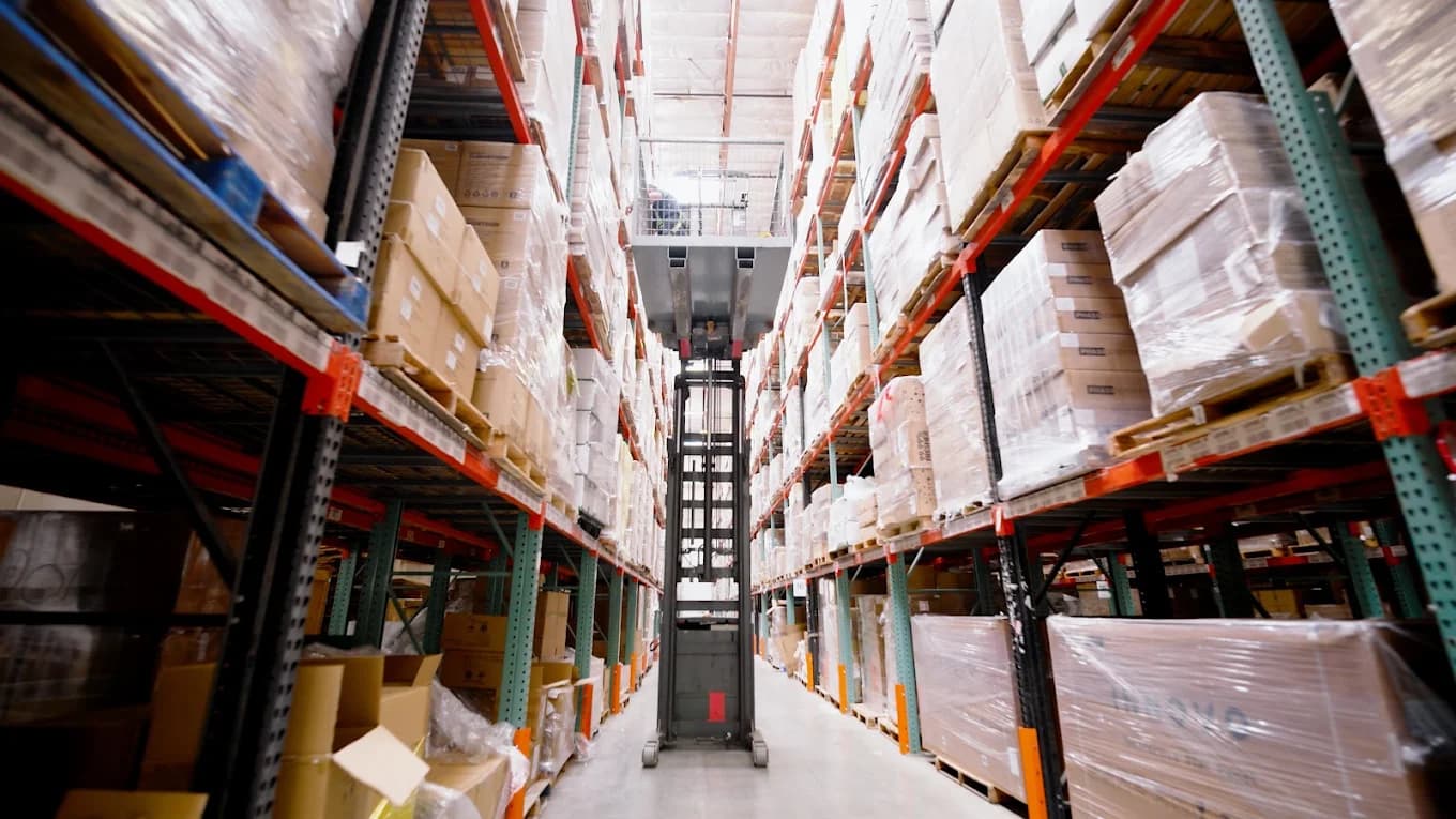 Forklift navigating a stocked warehouse storage aisle