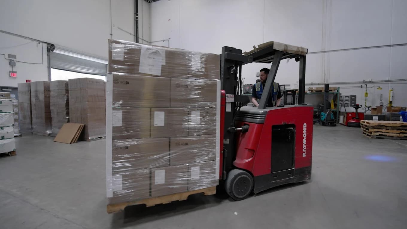 Warehouse associate operating a forklift to move a palletized order